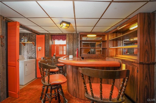 bar with carpet floors, a paneled ceiling, and wood walls