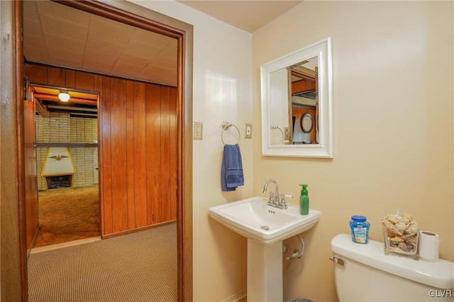 bathroom featuring wood walls and toilet