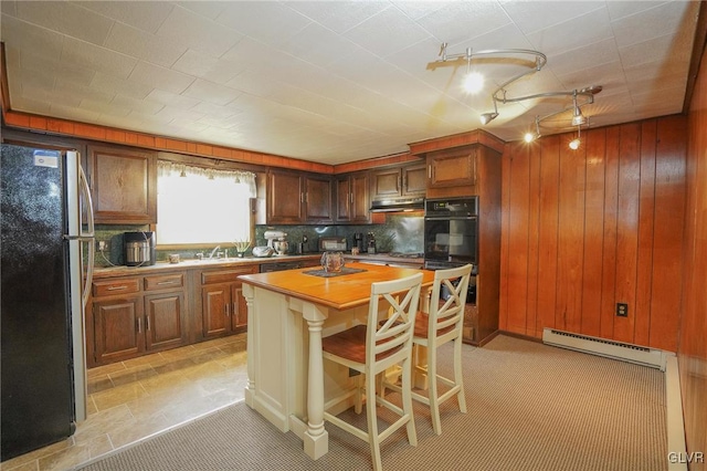 kitchen with tasteful backsplash, a kitchen island, black appliances, a kitchen breakfast bar, and a baseboard radiator