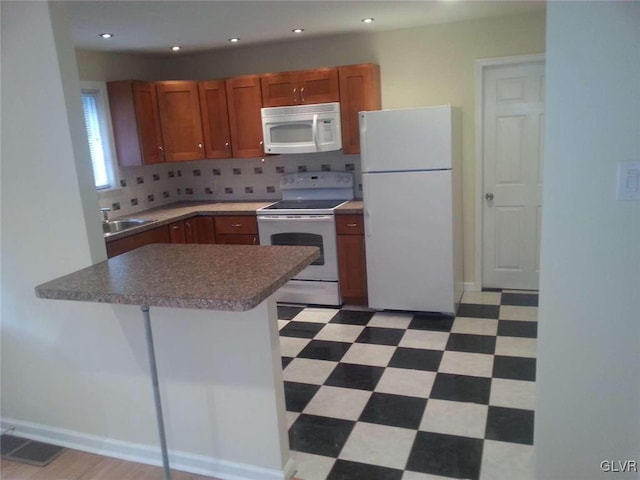 kitchen featuring decorative backsplash, white appliances, kitchen peninsula, and sink