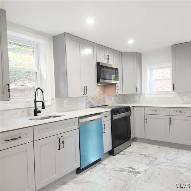 kitchen featuring stainless steel appliances, backsplash, sink, and a wealth of natural light