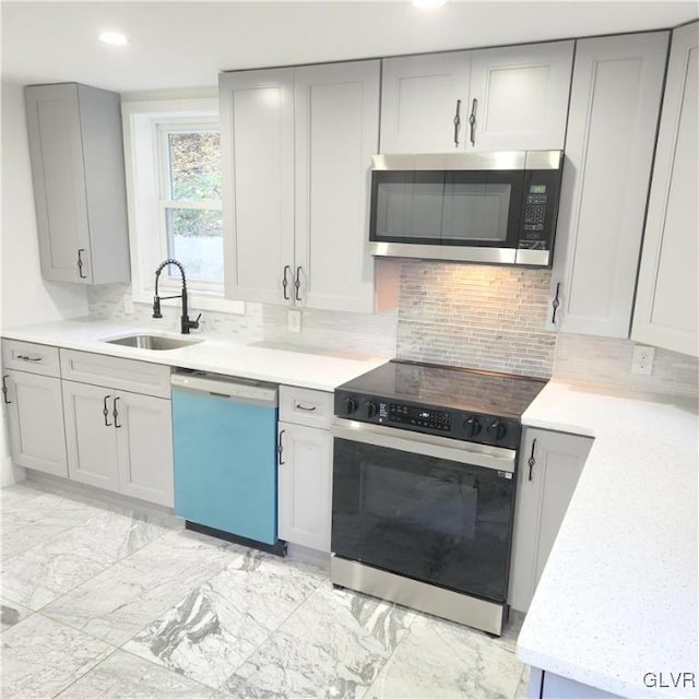 kitchen featuring tasteful backsplash, gray cabinets, appliances with stainless steel finishes, and sink