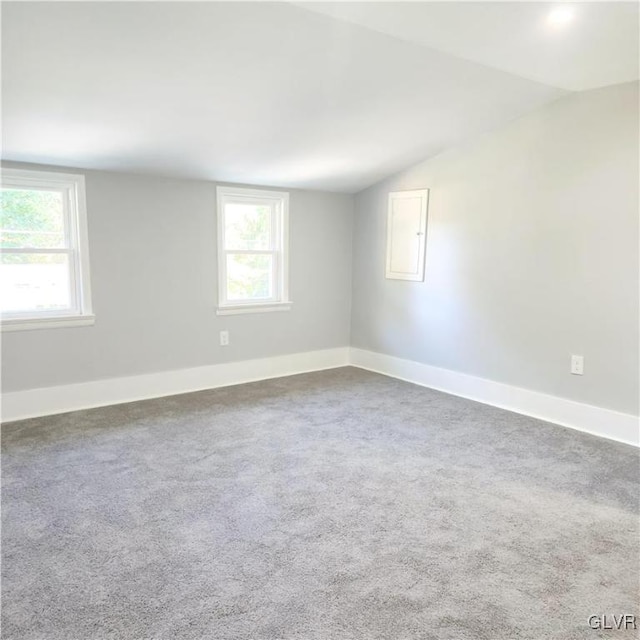 unfurnished room featuring lofted ceiling and dark colored carpet