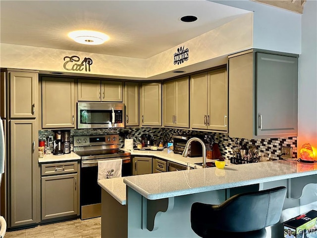 kitchen featuring stainless steel appliances, a breakfast bar area, gray cabinets, and kitchen peninsula