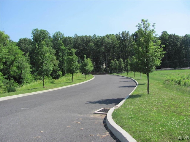 view of street with a wooded view and curbs