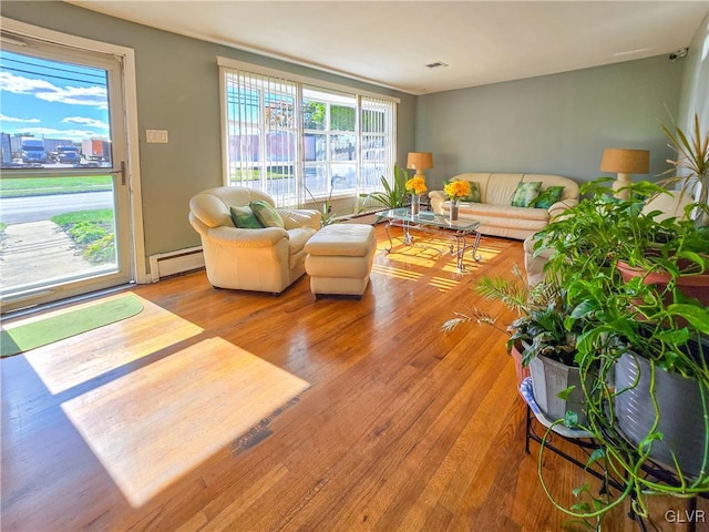 living room with a baseboard heating unit and light hardwood / wood-style flooring