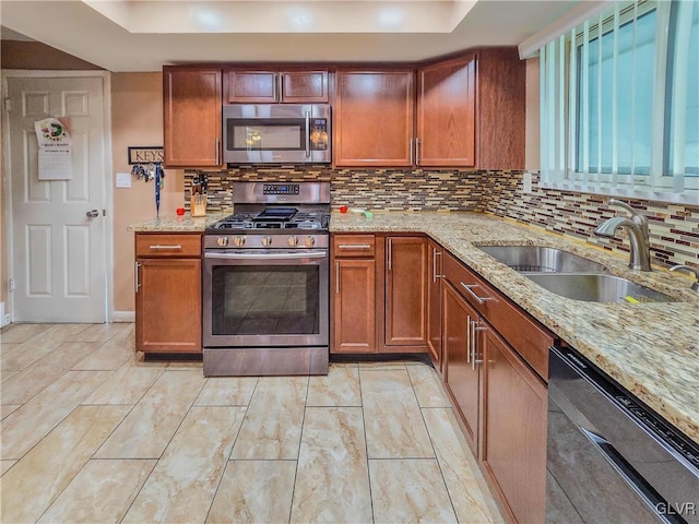 kitchen with light stone countertops, stainless steel appliances, sink, and tasteful backsplash