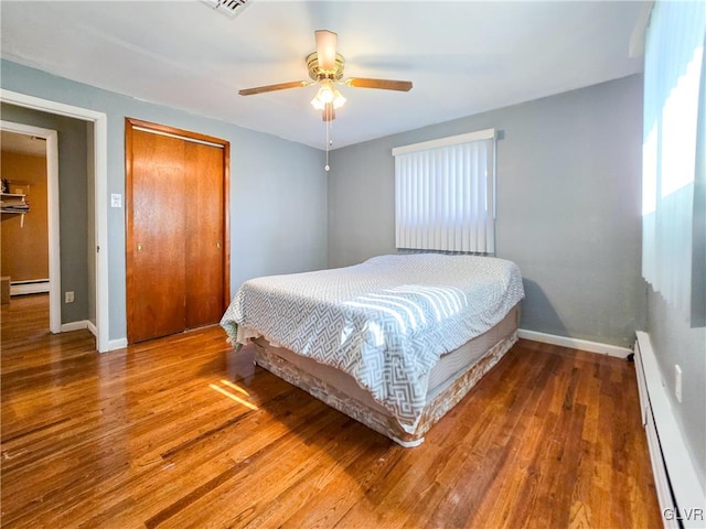 bedroom featuring baseboard heating, hardwood / wood-style flooring, and ceiling fan