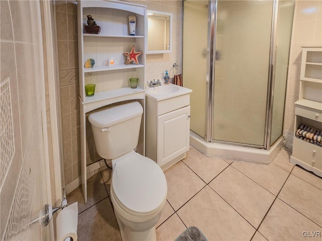 bathroom featuring toilet, tile patterned floors, tile walls, a shower with door, and vanity