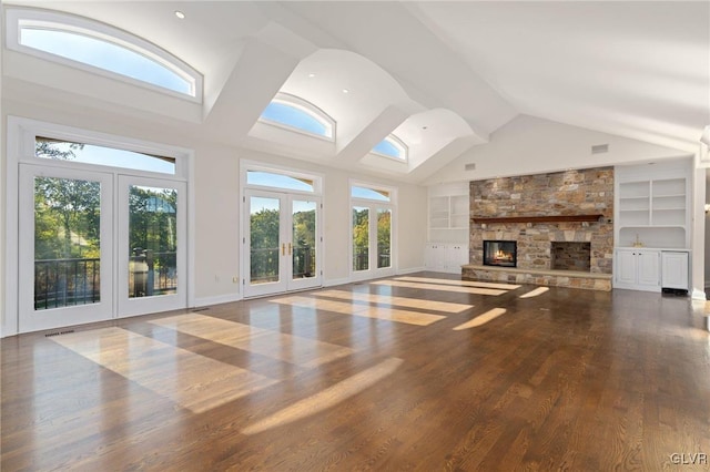 unfurnished living room featuring built in features, french doors, high vaulted ceiling, a fireplace, and hardwood / wood-style floors