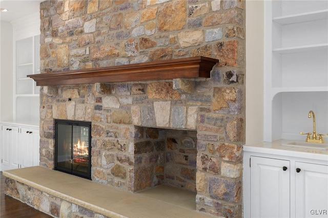 interior details featuring hardwood / wood-style floors, sink, and a stone fireplace