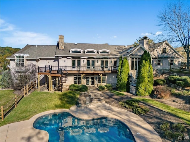 back of house featuring a pool side deck, a lawn, and a patio area