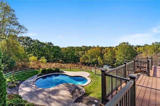 view of swimming pool featuring a wooden deck, a yard, and a patio area