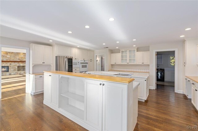 kitchen with white cabinets, white appliances, a kitchen island, dark hardwood / wood-style flooring, and butcher block counters