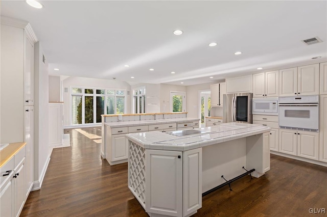 kitchen featuring white appliances, a kitchen island with sink, white cabinetry, tile countertops, and dark hardwood / wood-style floors