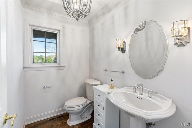 bathroom with ornamental molding, sink, hardwood / wood-style flooring, a notable chandelier, and toilet