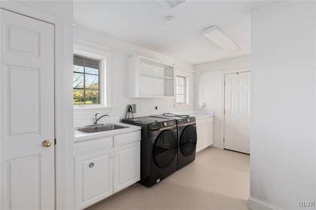 laundry room featuring washing machine and clothes dryer, cabinets, and sink