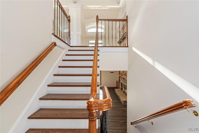 stairway featuring a stone fireplace and wood-type flooring