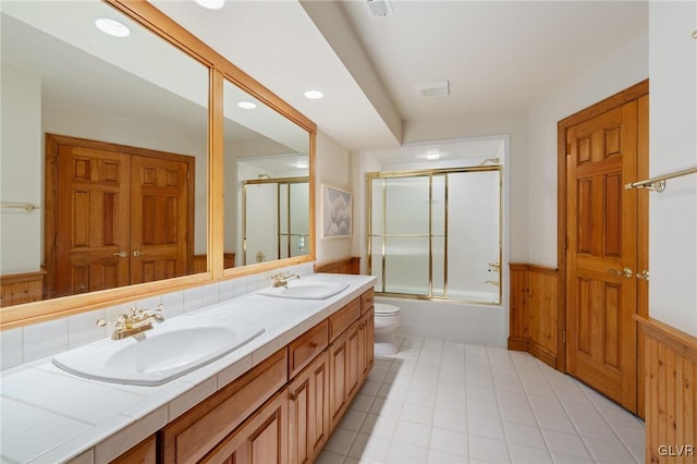 full bathroom with vanity, wood walls, toilet, and enclosed tub / shower combo