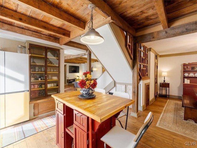 dining space featuring beamed ceiling, light hardwood / wood-style floors, and wooden ceiling