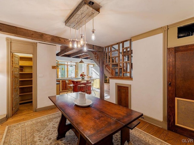 dining space with beam ceiling and light wood-type flooring