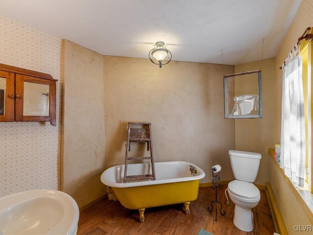 bathroom featuring sink, toilet, wood-type flooring, and a bath