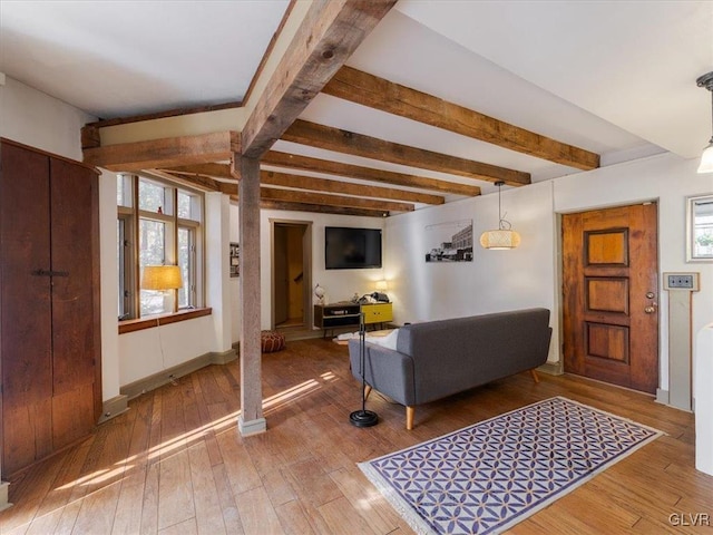 living room featuring beamed ceiling, a healthy amount of sunlight, and wood-type flooring