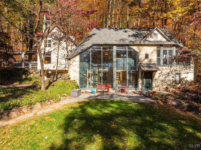 rear view of house featuring a sunroom and a lawn