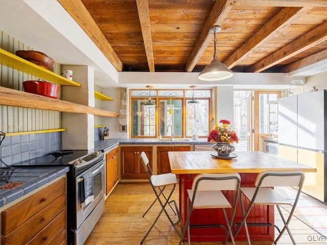 kitchen featuring stainless steel range with electric stovetop, a breakfast bar, white refrigerator, light hardwood / wood-style floors, and wood ceiling