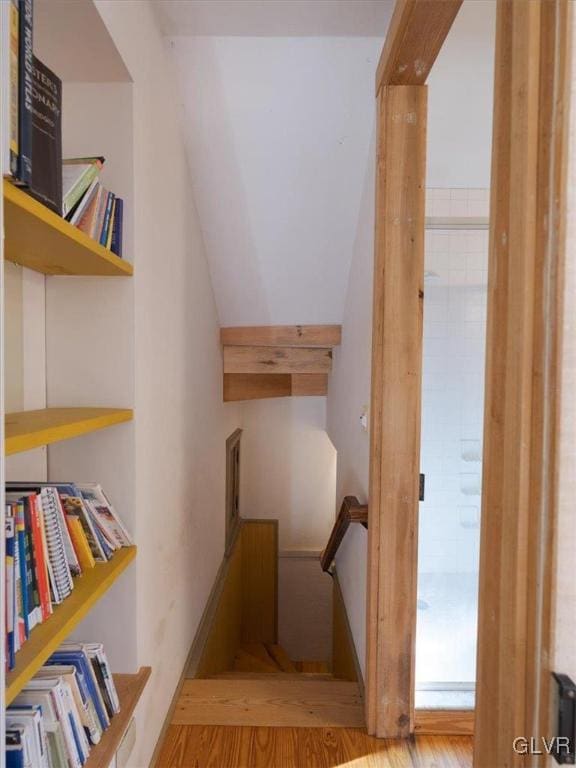 staircase with wood-type flooring and vaulted ceiling