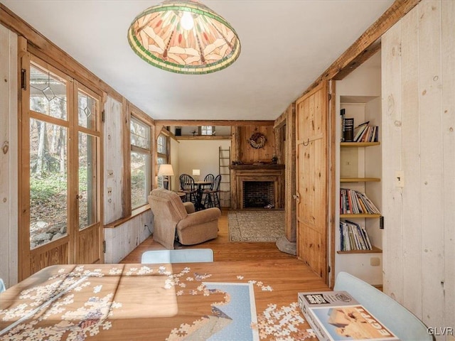 living area featuring built in features, light hardwood / wood-style flooring, and wood walls