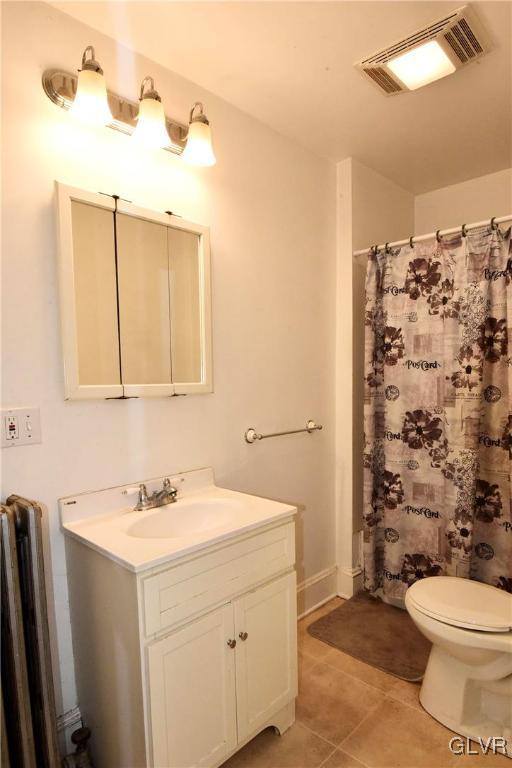 bathroom featuring radiator heating unit, vanity, walk in shower, tile patterned flooring, and toilet