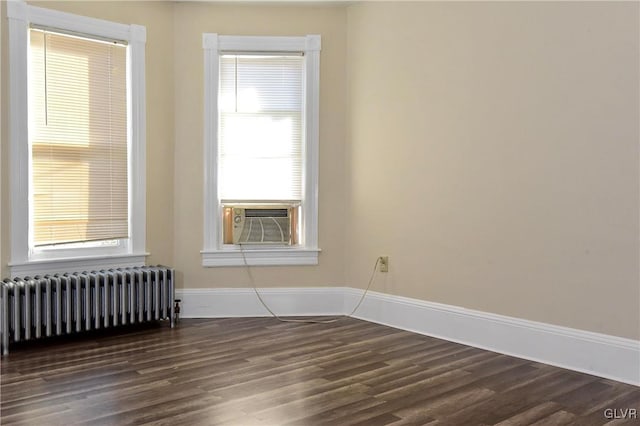 spare room featuring cooling unit, dark wood-type flooring, and radiator heating unit