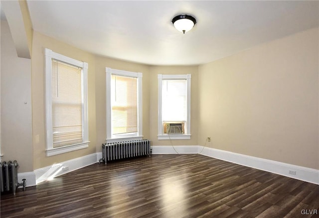 empty room featuring cooling unit, radiator heating unit, and dark hardwood / wood-style flooring