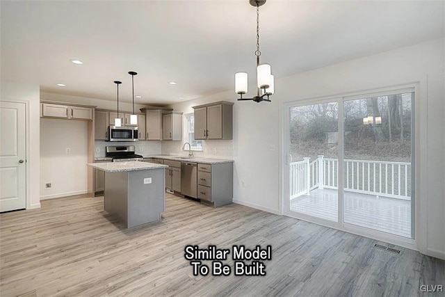 kitchen featuring appliances with stainless steel finishes, pendant lighting, a center island, and light hardwood / wood-style flooring