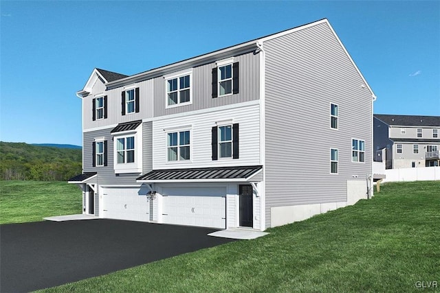 view of front of house with a standing seam roof, a front lawn, an attached garage, and aphalt driveway