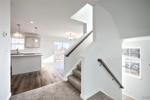 stairs featuring wood finished floors, recessed lighting, carpet, an inviting chandelier, and baseboards