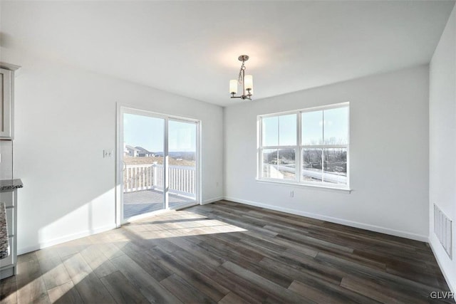 empty room featuring dark wood-type flooring, baseboards, visible vents, and a chandelier