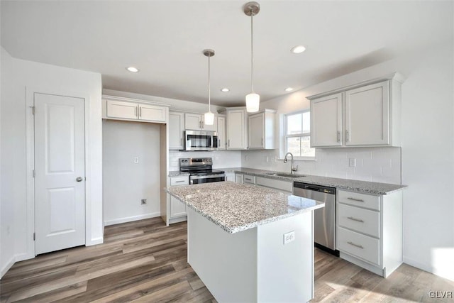 kitchen with tasteful backsplash, a kitchen island, appliances with stainless steel finishes, wood finished floors, and a sink