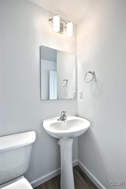 bathroom with toilet, baseboards, and wood finished floors