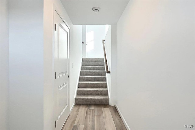 hall with stairs, light wood-style flooring, and baseboards