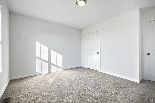 spare room featuring baseboards, visible vents, and carpet floors