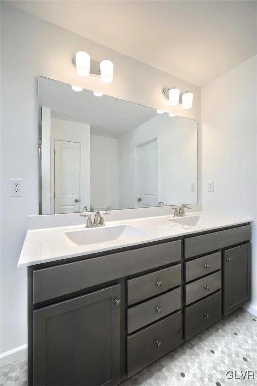 full bath featuring double vanity, baseboards, and a sink