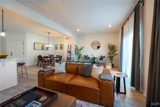 living room featuring light wood-type flooring and a notable chandelier