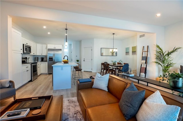 living room with a notable chandelier and light hardwood / wood-style floors