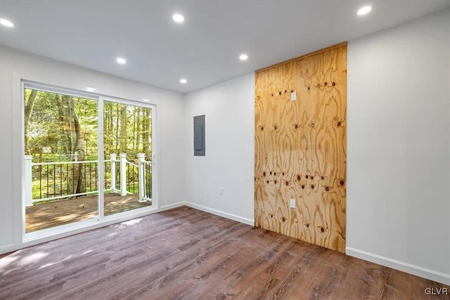 unfurnished room with electric panel and hardwood / wood-style floors