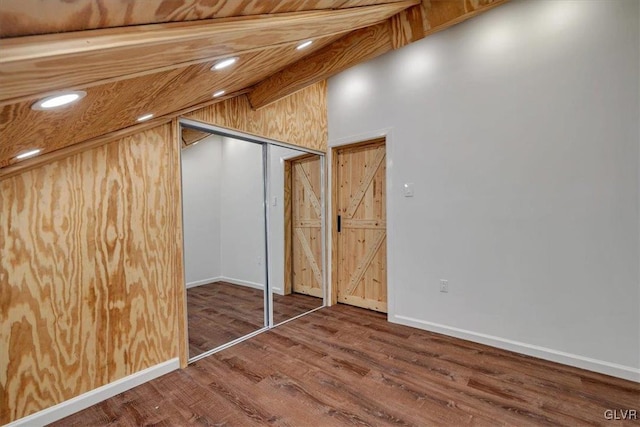 interior space with wood-type flooring, vaulted ceiling with beams, and a closet