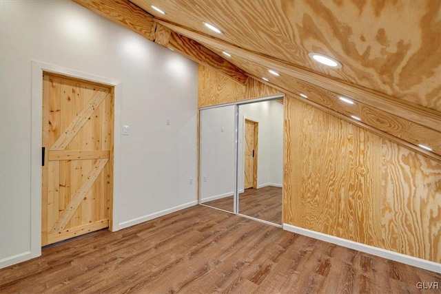 additional living space with wood walls, hardwood / wood-style floors, and vaulted ceiling