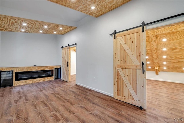 unfurnished living room with a barn door and hardwood / wood-style floors