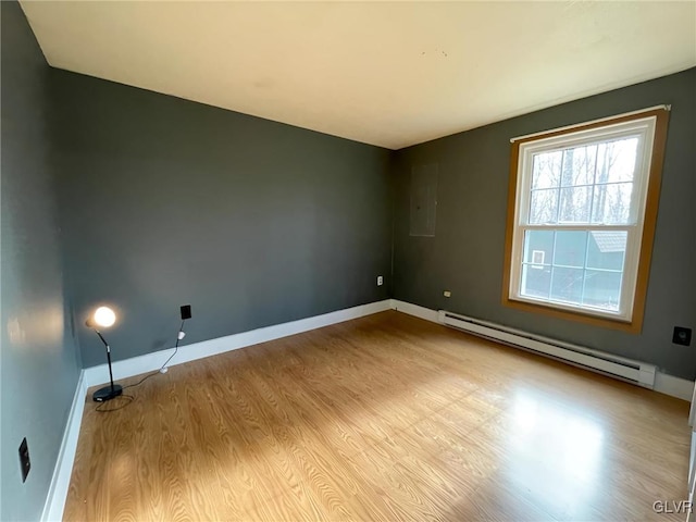 empty room featuring baseboard heating, electric panel, and light hardwood / wood-style floors